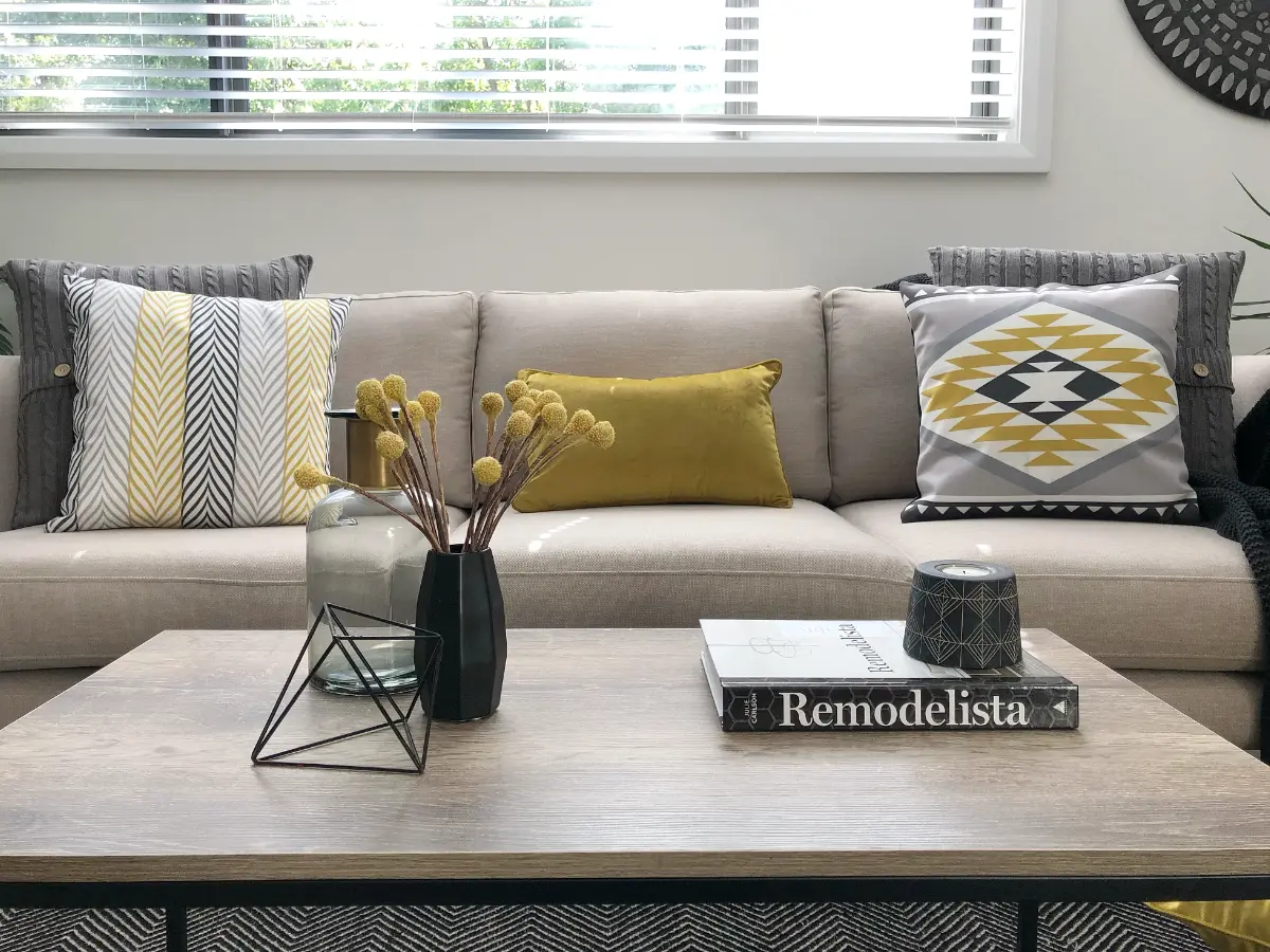 Living room fitted out with urban modern decor including mustard coloured cushions, a navy throw rug and and black table yellow chevron designs