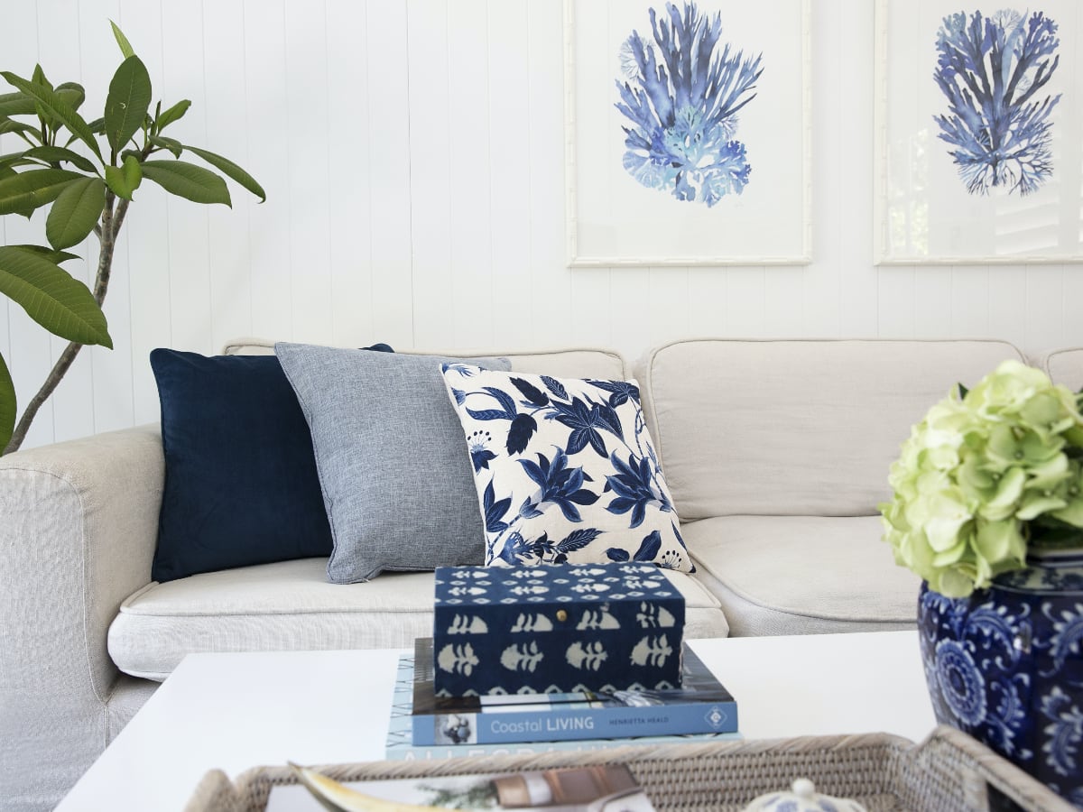 A 3 cushion scene featuring blue floral designs on a simple sofa.