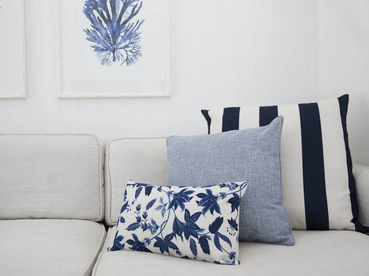 A set of three Hamptons cushions on a sofa.