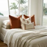 Anna cushions on bed with rust tones, small motifs and striped lumbar cushion.
