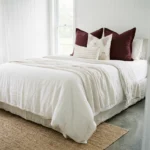 Elle cushions styled on bed with burgundy, floral and striped neutral cushions.