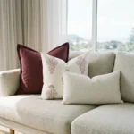 Elle cushions on sofa with burgundy, cream patterned and textured white designs.