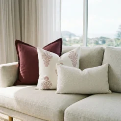 Elle cushions on sofa with burgundy, cream patterned and textured white designs.