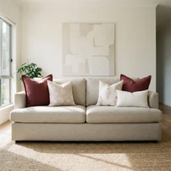 Elle cushions styled on sofa with burgundy, beige and subtle striped cushions.
