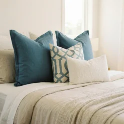 Eva cushions styled on bed with teal, geometric print and soft neutral accents.