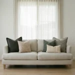 Jude cushions arranged on sofa with dark green, cream and striped patterned cushions.