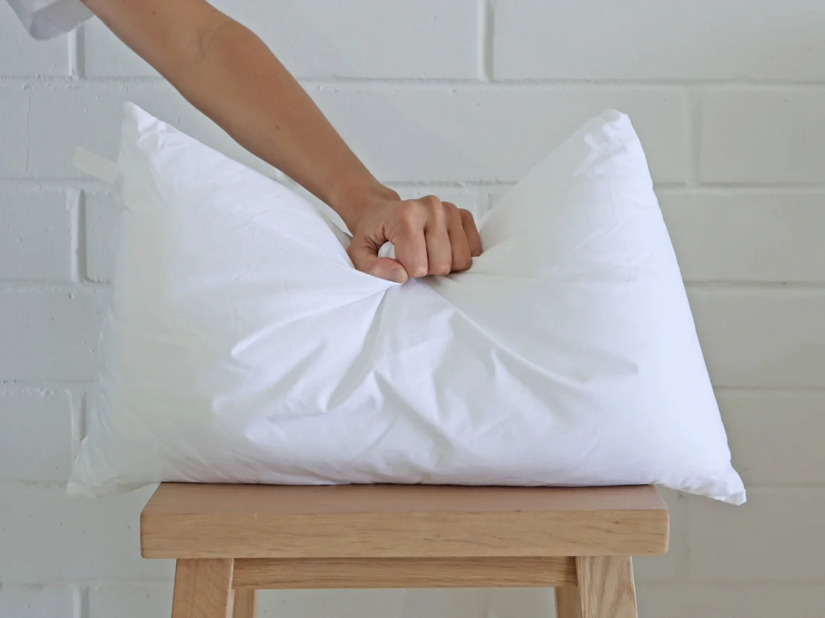 A cushion insert on a stool is being pushed by a hand.