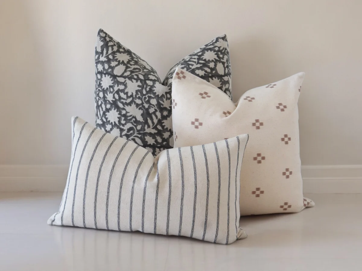 A three set of three cushions displayed in front of a minimalist wall.