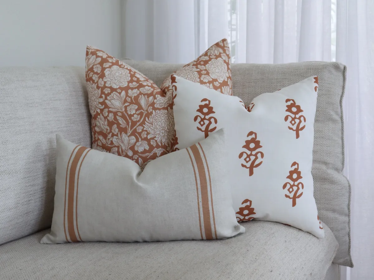 A set of three different throw cushion sizes styled on the corner of a sofa.