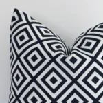 The corner of this outdoor square cushion cover is shown close up. The geometric design and black and white colour are shown in greater detail.