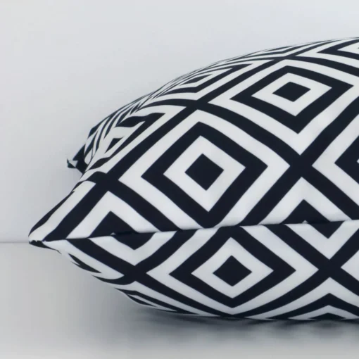 Square black-and-white cushion laid flat. This view shows the geometric style and outdoor fabric from side on.