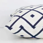 Geometric navy beige cushion laid horizontally. This perspective shows the edge of the outdoor fabric and its square shape.
