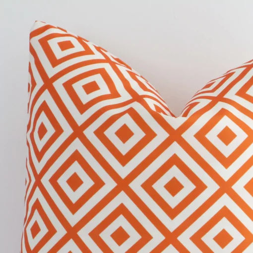 A macro image of the top left corner of this geometric outdoor cushion. It is possible to see the finer detail of the square shape and orange colour.