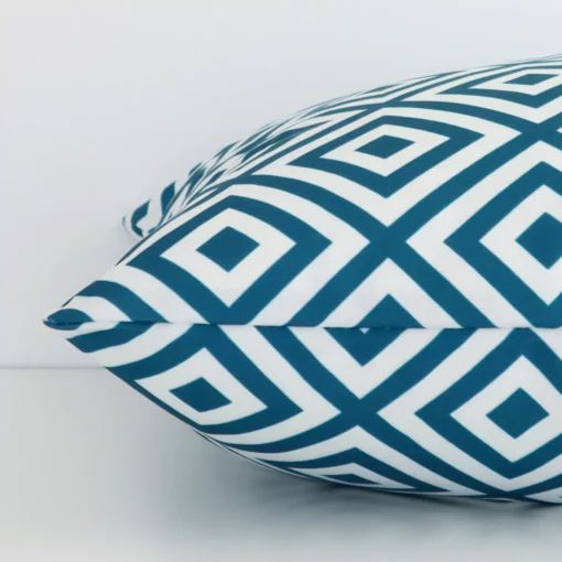 Close side shot of this teal outdoor cushion cover. The viewpoint shows how the square design and outdoor decorative finish meet along its edge.