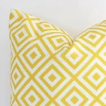 Close range image of yellow geometric cushion. The square size and outdoor material can be seen in detail.