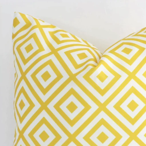 Close range image of yellow geometric cushion. The square size and outdoor material can be seen in detail.