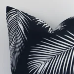 Focused view of palm-designed square cushion cover. The shot shows details of its outdoor material and black and white colour.