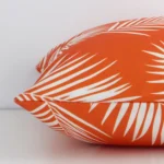 Outdoor orange cushion laying on its side. The palm design and its square size are visible.