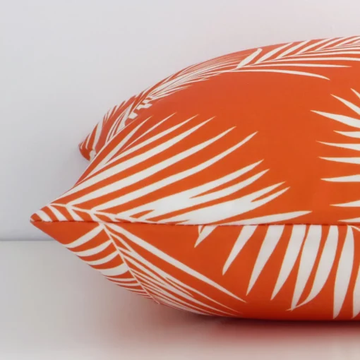 Outdoor orange cushion laying on its side. The palm design and its square size are visible.