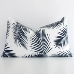 Rectangular palm-designed cushion cover in black-and-white colour sitting upright in front of a wall. It has been made from a quality outdoor material.
