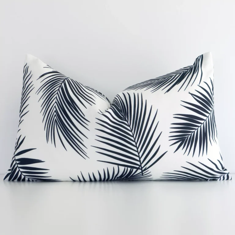 Rectangular palm-designed cushion cover in black-and-white colour sitting upright in front of a wall. It has been made from a quality outdoor material.