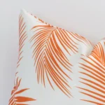 A rectangular orange outdoor cushion cover’s corner is shown in more detail. It is possible to see the palm decorative finish in much more detail.