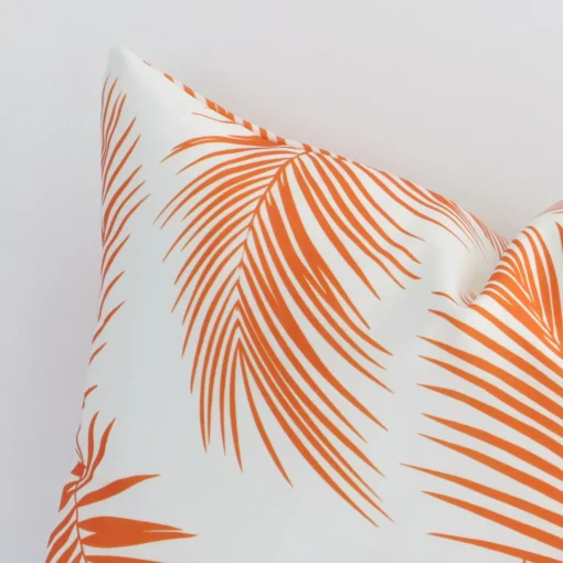 A rectangular orange outdoor cushion cover’s corner is shown in more detail. It is possible to see the palm decorative finish in much more detail.
