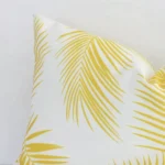 Zoomed photo of the top left corner of this yellow palm printed rectangle cushion cover. The image clearly shows the outdoor material.