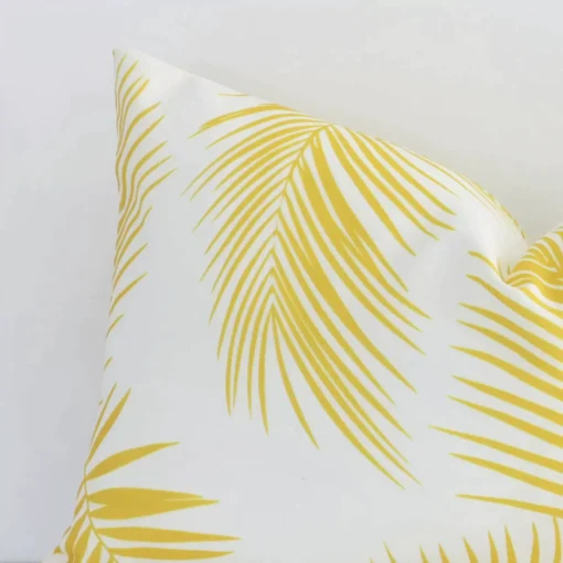 Zoomed photo of the top left corner of this yellow palm printed rectangle cushion cover. The image clearly shows the outdoor material.