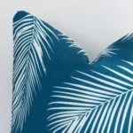 A very close image of the corner of a palm designed outdoor cushion.The finer detail of the square shape and teal colour are visible.