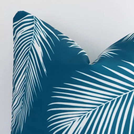 A very close image of the corner of a palm designed outdoor cushion.The finer detail of the square shape and teal colour are visible.