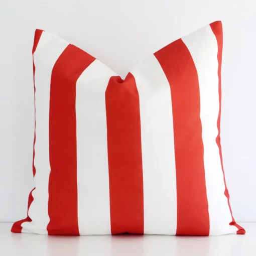 A white wall that has a striped red cushion cover positioned in front of it. It has an exquisite outdoor material and a lovely large size.