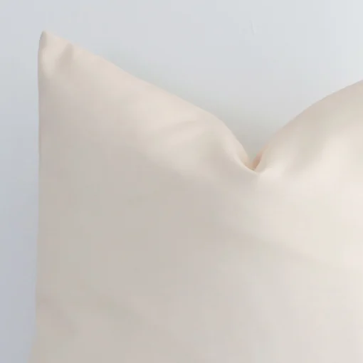 A zoomed in photo of the corner of a beige solid-coloured cushion that has an outdoor fabric and a square shape.