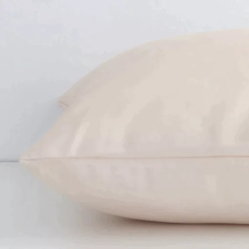 Square solid-coloured cushion in beige colour laying flat. The viewpoint highlights the seams of the outdoor fabric.