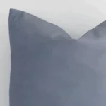 The corner of this outdoor square cushion cover is shown close up. The solid-coloured design and grey colour are shown in greater detail.