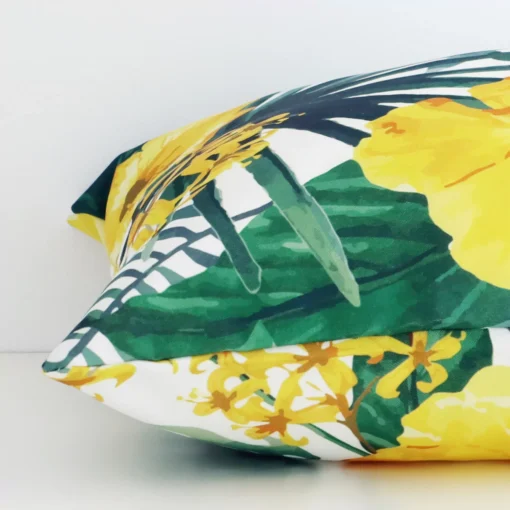 Side angle shot of outdoor square cushion cover. The yellow hue and floral style are shown along its seams.