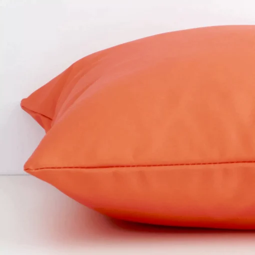 Lateral view of front and back panels of this solid-coloured outdoor cushion cover in a square size and with coral colouring.