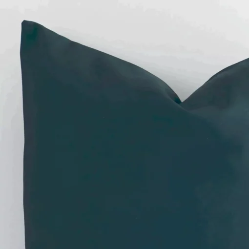 Close up view showing a corner of this solid-coloured dark green linen cushion in a square size.