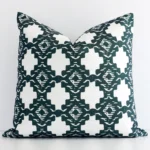 An attractive patterned linen cushion in front of a white wall. It has a square shape and is green in colour.