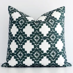 An attractive patterned linen cushion in front of a white wall. It has a square shape and is green in colour.