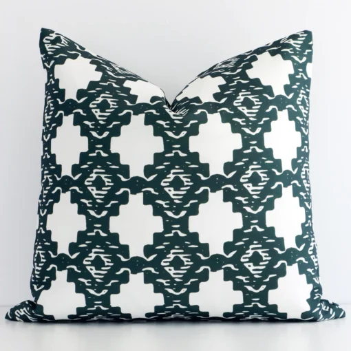 An attractive patterned linen cushion in front of a white wall. It has a square shape and is green in colour.