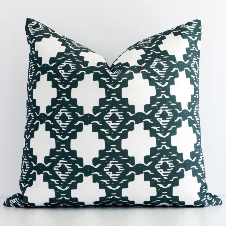 An attractive patterned linen cushion in front of a white wall. It has a square shape and is green in colour.