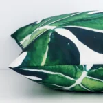 Side angle of green tropical cushion cover that has linen fabric and a square size.