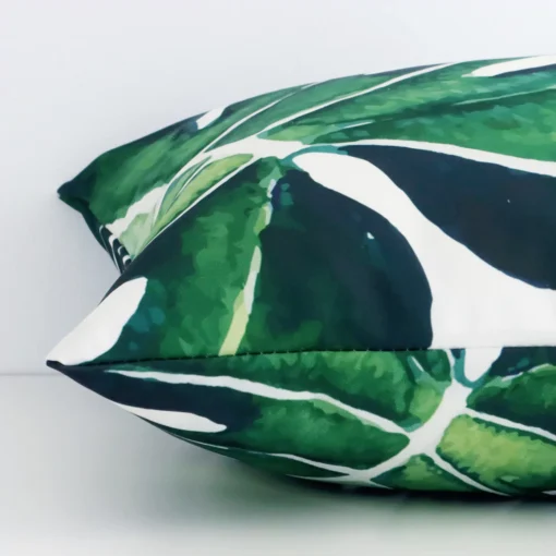 Side angle of green tropical cushion cover that has linen fabric and a square size.