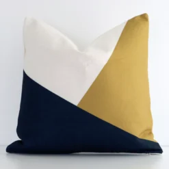 A lovely square colourful cushion cover arranged in front of a white wall. The geometric style complements the linen material.