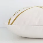 Horizontal edge view of front and back panels of a geometric linen cushion in a square size and with gold mustard print.