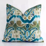 Colourful square cushion leans elegantly against a white wall. It has been crafted from a high quality linen material and has a square shape.