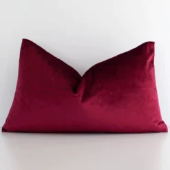 A hero shot of a solid-coloured rectangle cushion cover. It is made from a deluxe velvet fabric and features a burgundy colour.