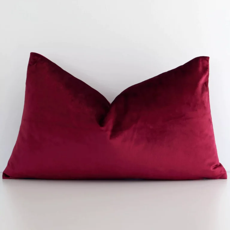 A hero shot of a solid-coloured rectangle cushion cover. It is made from a deluxe velvet fabric and features a burgundy colour.