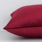 Side angle of burgundy solid-coloured cushion cover that has velvet fabric and a rectangle size.